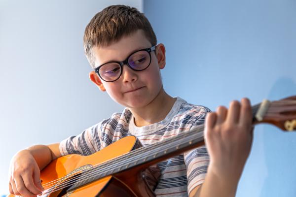 un garçon joue de la guitare sèche