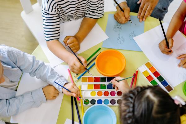 des enfants font de la peinture autour d'une table